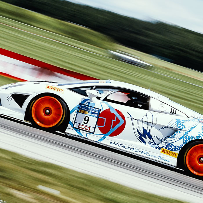 Race car in motion featuring vibrant orange wheels and distinctive branding, representing the Canadian Sport Compact Series, showcasing C17media's involvement in motorsport media and installation projects.