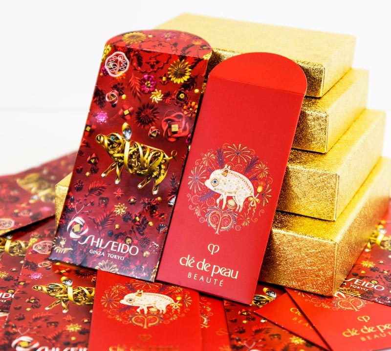 Shiseido packaging featuring decorative designs with a pig and chameleon, surrounded by gold gift boxes, highlighting brand aesthetics and luxury.