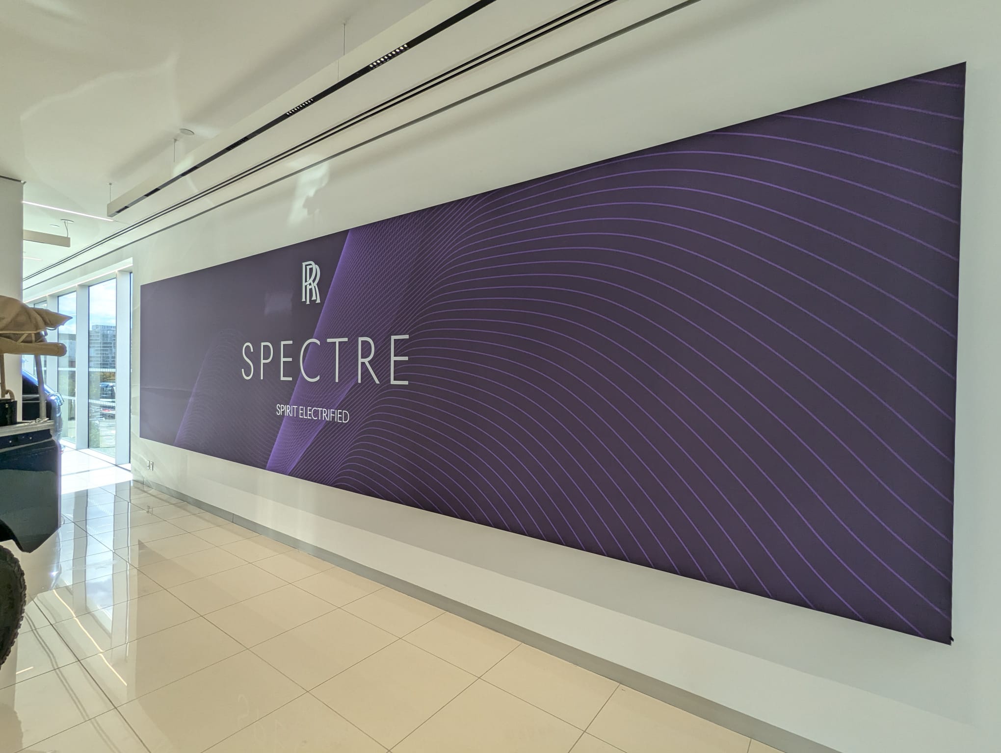 Large format fabric print displaying "SPECTRE" and "SPIRIT ELECTRIFIED" on a sleek purple background, enhancing brand visibility in a modern interior setting.